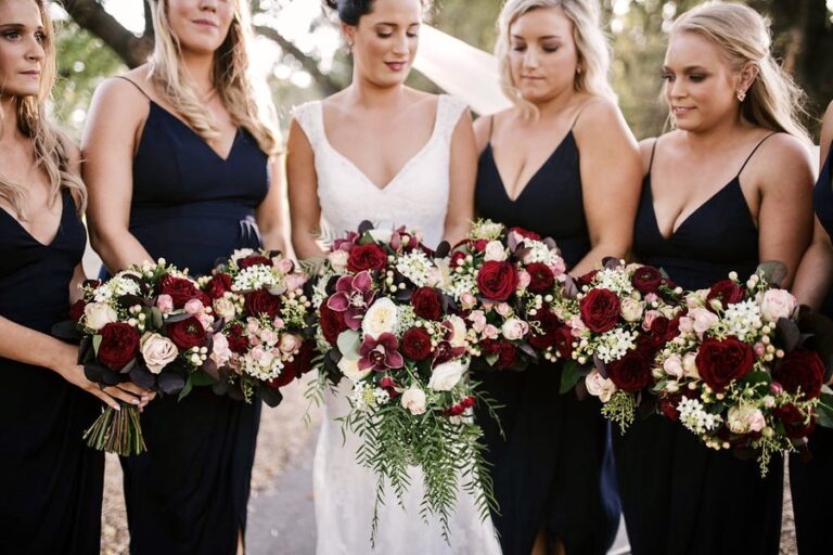Bridesmaids holding burgundy and blush rose bouquets