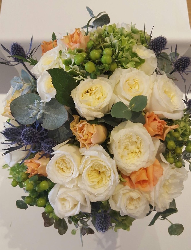 Bridal bouquet of white garden roses, peach roses, thistle and hypericum berries